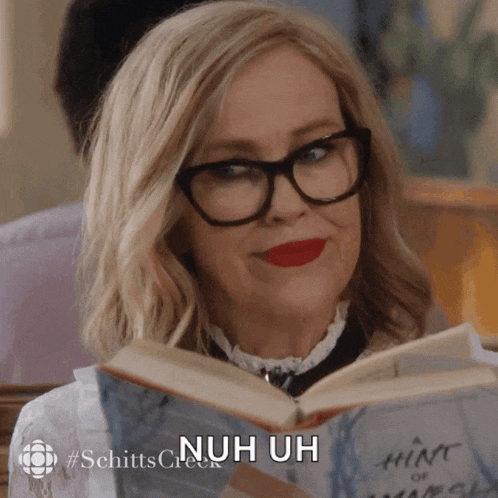 a woman wearing glasses is reading a book and says 