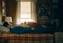 a man in a superhero costume is laying on a bed with his dog