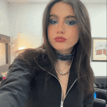a woman wearing a choker necklace and a black jacket takes a selfie