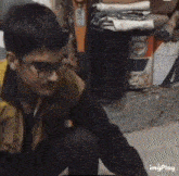 a man wearing glasses is squatting down in front of a barrel