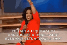 a woman in a red dress is holding a microphone and says you get a tequila shot