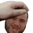 a pixelated image of a man 's face with a hand holding his head .