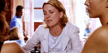 a woman is sitting at a table with another woman and says so gay