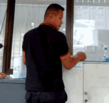a man in a black shirt stands in front of a window with a sticker on it that says ' a ' on it