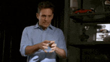 a man in a blue shirt is standing in front of a shelf with a toy car on it