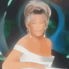 a woman in a white off the shoulder dress is looking down