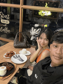 a man and a woman sit at a table with plates of food and a sign that says start your day with coffee