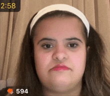 a girl with a white headband is making a funny face with the time 2:58 behind her