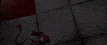 a person is standing on a tiled floor in a dark room with a red object in the background .