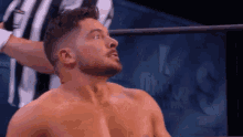 a man with a beard is standing in a wrestling ring without a shirt on .