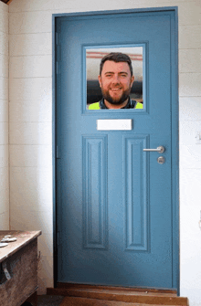 a man in a yellow vest stands in a blue door