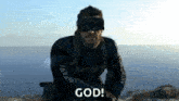 a man wearing a virtual reality headset is sitting in front of a body of water and says god .