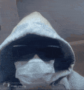 a person wearing a hoodie and sunglasses has a mask on