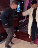 two men are dancing in a living room with a tv in the background that says ' netflix ' on it