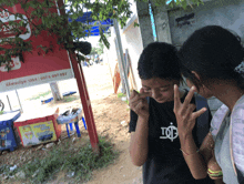 a girl wearing a black shirt with the letter i on it looks at something