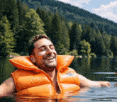 a man wearing an orange life vest is smiling in the water