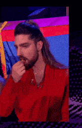a man with long hair and a beard is wearing a red shirt