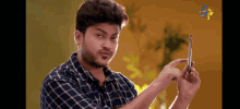 a man in a plaid shirt is holding a cellphone in his hand