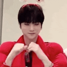 a young man wearing a red shirt and tie is making a heart with his hands .
