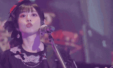 a woman singing into a microphone while playing a guitar