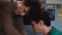 two young men with curly hair are looking at each other in a room