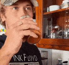a man wearing a pink floyd shirt is drinking from a glass