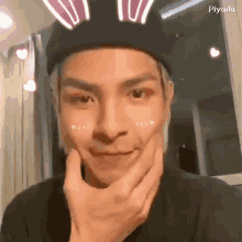 a man wearing a black hat with bunny ears is making a funny face
