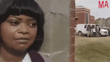 a woman is standing in front of a brick building and a white van is parked in front of her