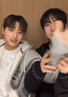 two young men are standing next to each other and one of them is wearing a jacket with the letter l on it