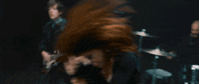 a woman with red hair sings into a microphone while a man plays a guitar