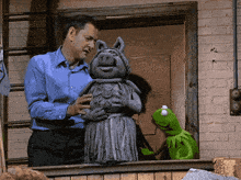 a man in a blue shirt holds a statue of a pig
