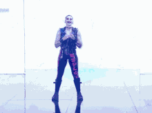 a man in a pink and black outfit is dancing in front of a blue wall .