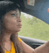 a woman is driving a car on a road and looking out the window .