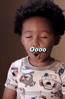 a little boy wearing a shirt with dogs on it making a funny face with the word oooo on his face