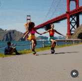 two rollerbladers are holding hands in front of a golden gate bridge