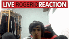 a man wearing headphones stands in front of a sign that says live rogerio reaction