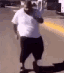 a man in a white shirt and black shorts is standing on the sidewalk .