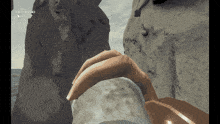 a screenshot of a video game shows a hand reaching up to a rock