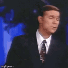 a man in a suit and tie is giving a speech in front of a cross ..
