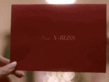a person is holding a red envelope that says x-bliss on it