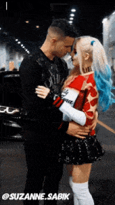 a woman in a harley quinn costume is kissing a man