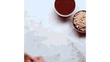a person is grating peanuts on a cutting board next to a bowl of sauce .