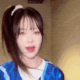 a girl with long hair in a ponytail is wearing a blue shirt