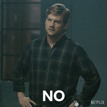 a man in a plaid shirt is standing with his hands on his hips and says no