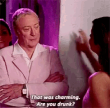 a man in a white suit is talking to a woman in a pink shirt .