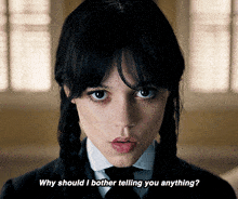 a woman in a suit and tie is asking why should i bother telling you anything