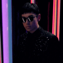 a man in a black shirt is standing in front of a purple and blue light .
