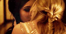 two women are hugging each other in a room and kissing .