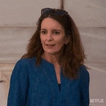 a woman wearing sunglasses and a blue jacket with netflix written on the bottom right
