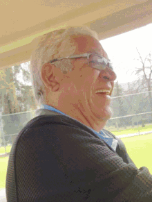 a man wearing glasses and a black jacket smiles